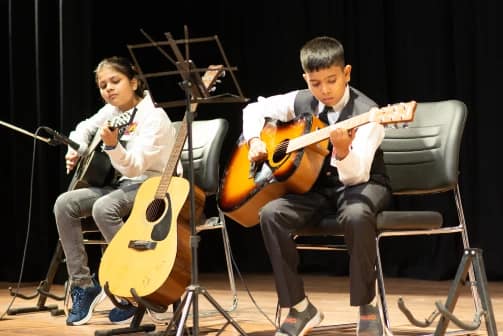 Music classes Two children from a music academy in Pune playing guitars on stage during a performance. pune